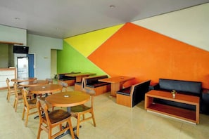 Un intérieur moderne avec des tables et des chaises rondes, un canapé et un motif géométrique sur le mur.