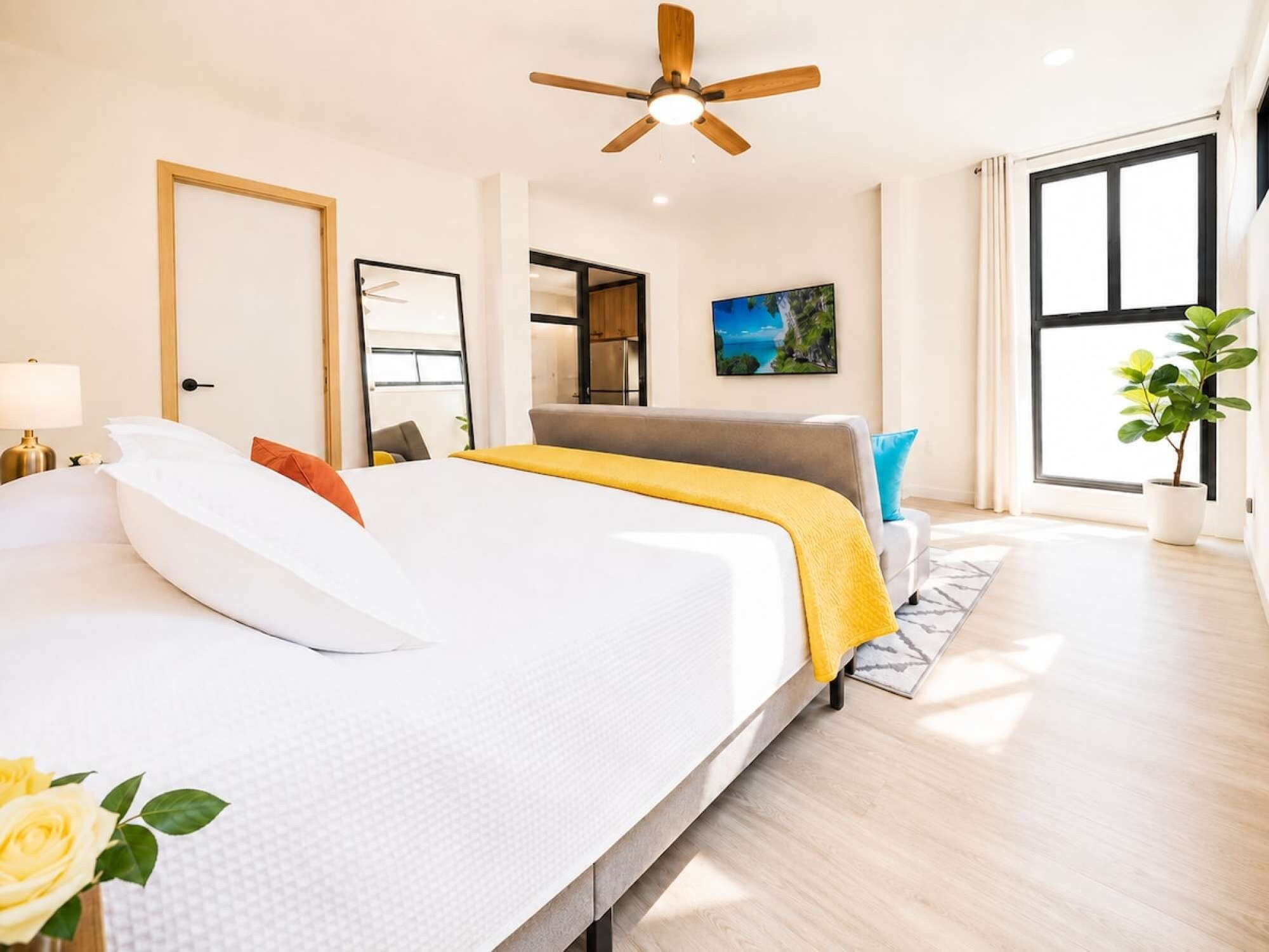 Une chambre moderne avec un grand lit, un ventilateur de plafond, une fenêtre avec des rideaux et une plante en pot.