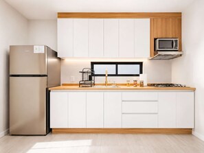 Eine moderne Küche mit einem eingebauten Kühlschrank, einer Mikrowelle und einem Gasherd.