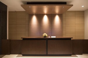 Un mostrador de recepción de diseño moderno, con iluminación empotrada y un jarrón con flores.