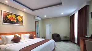 Quarto de hotel com cama, escrivaninha e cadeira.