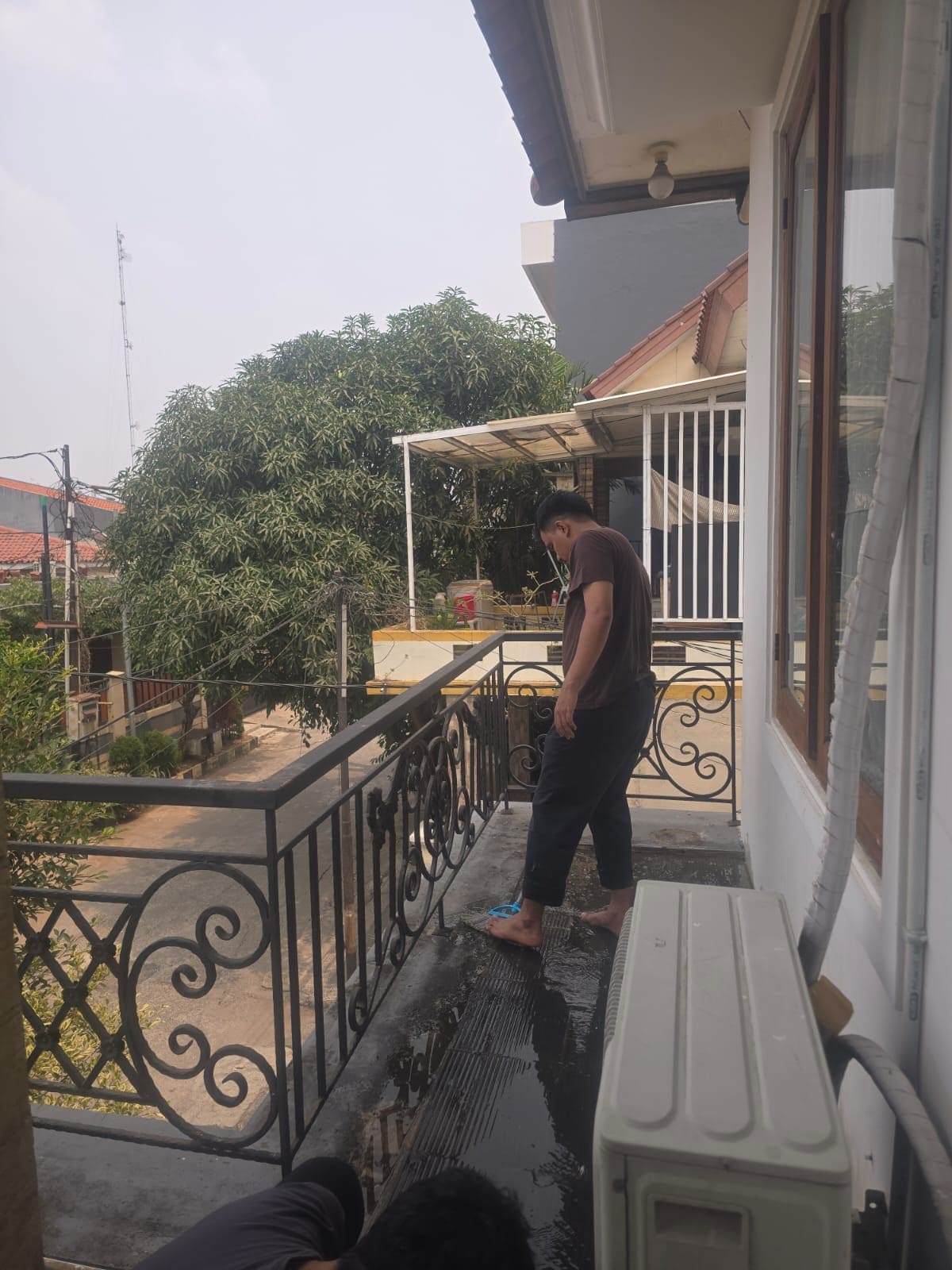 A balcony with a metal railing, a white wall, and a window.