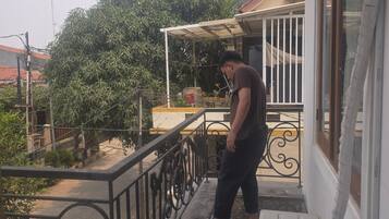 A balcony with a metal railing, a white wall, and a window.