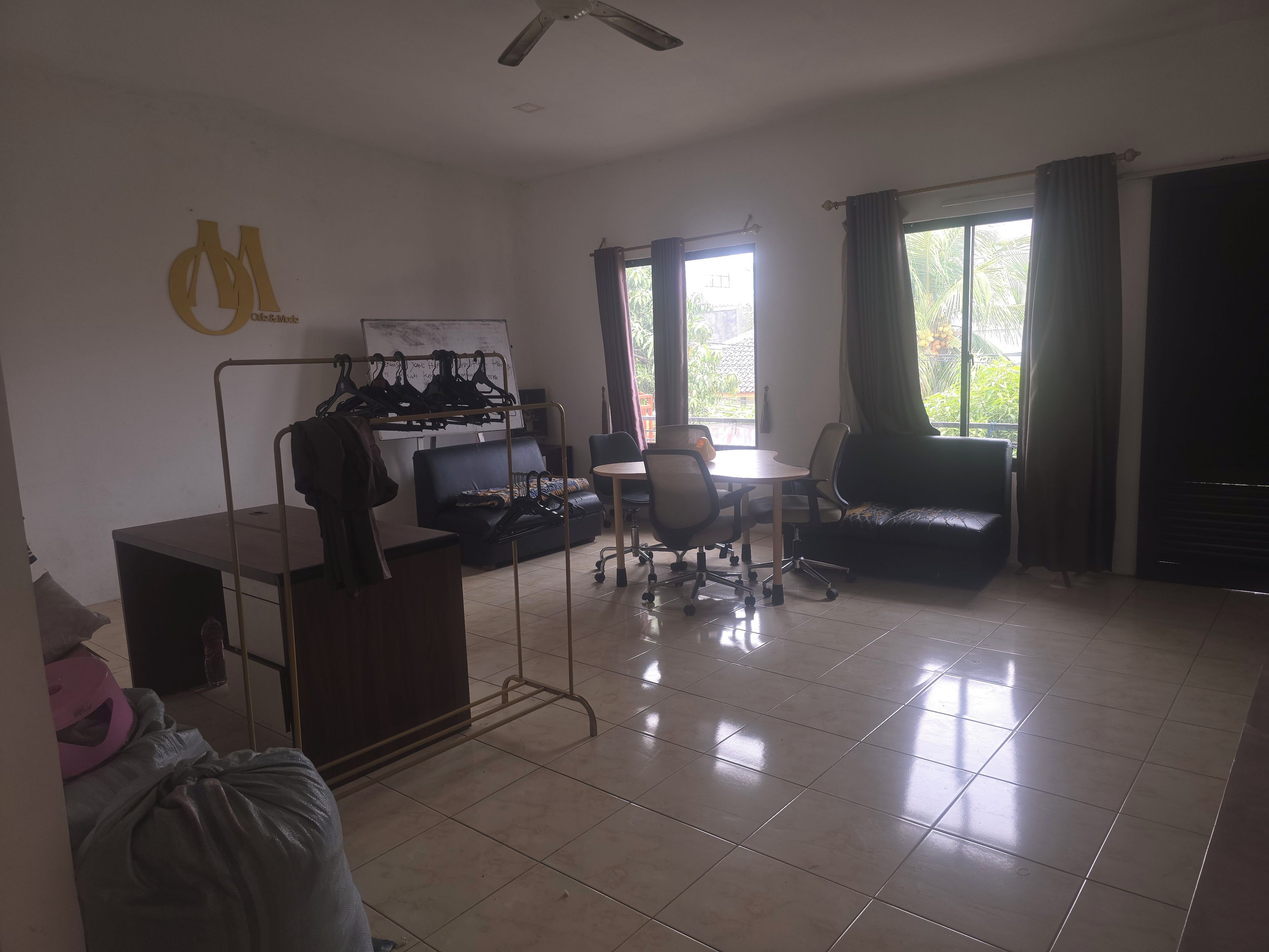 A room with a dining table, chairs, a sofa, a coat rack, and a whiteboard.