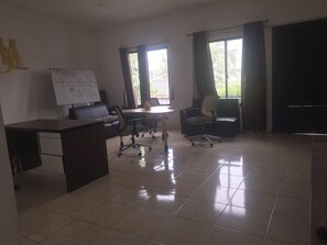 A conference room with a whiteboard, a desk, two chairs, and a large window with curtains.