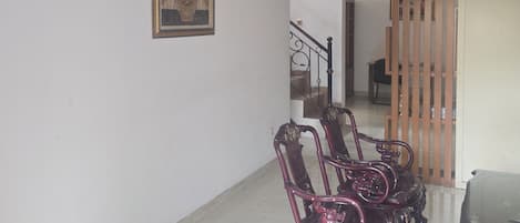 A spacious room with a high ceiling, a staircase, and a wooden partition.