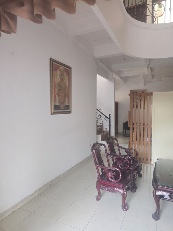A spacious room with a high ceiling, a staircase, and a wooden partition.