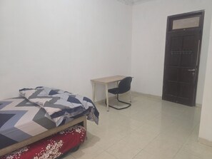 A bedroom with a bed, a desk, and a door.