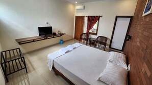 Una habitación de hotel con una cama, un escritorio con televisor, una silla y una ventana con cortinas.