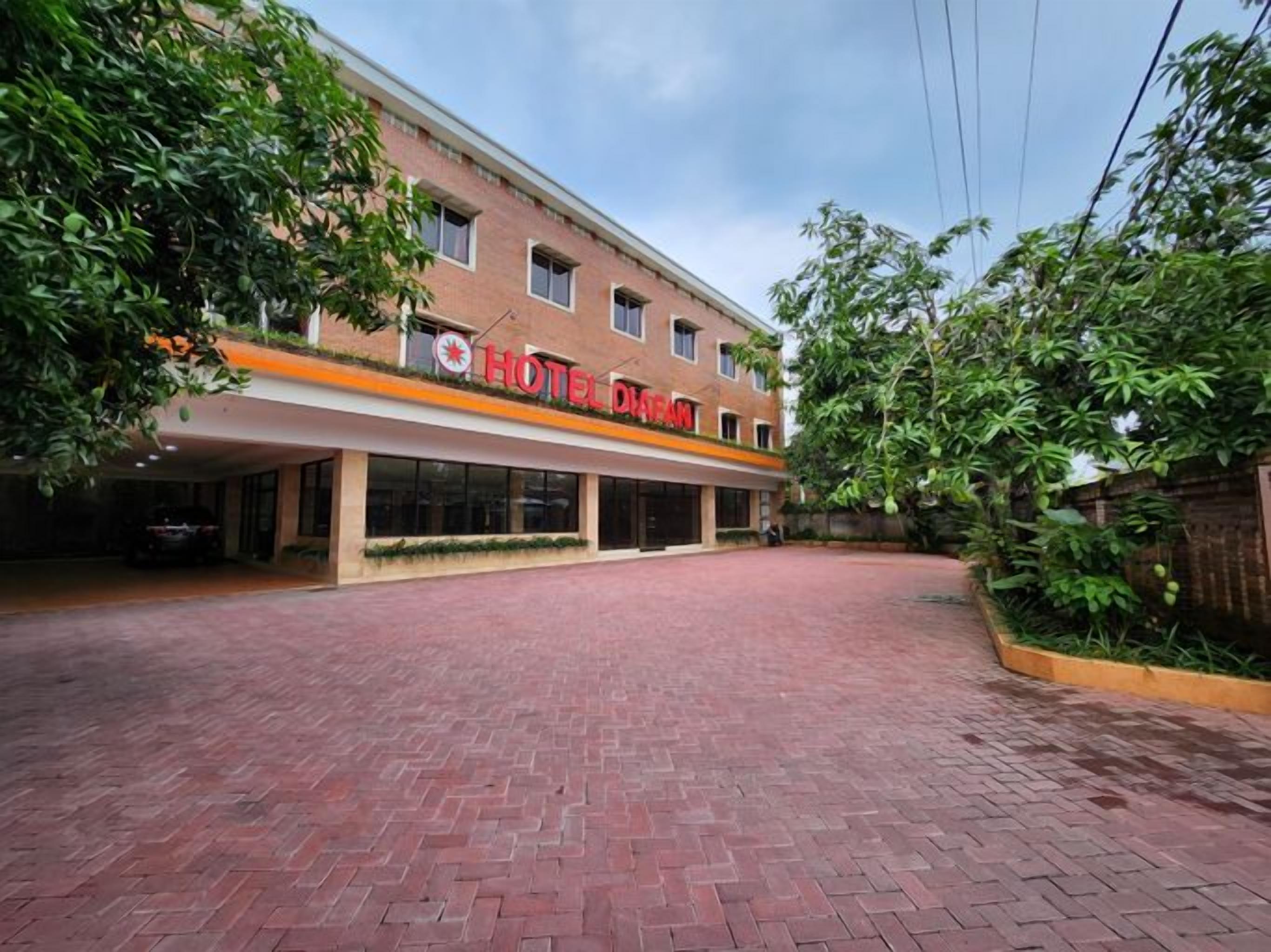 A hotel with a red-brick facade, a covered entrance, and a paved driveway.
