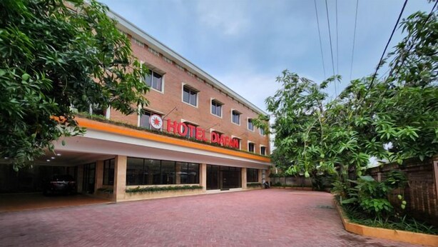 Un hotel con fachada de ladrillo rojo, un acceso cubierto y un camino de entrada pavimentado.