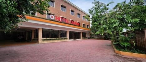 Un hotel con fachada de ladrillo rojo, un acceso cubierto y un camino de entrada pavimentado.