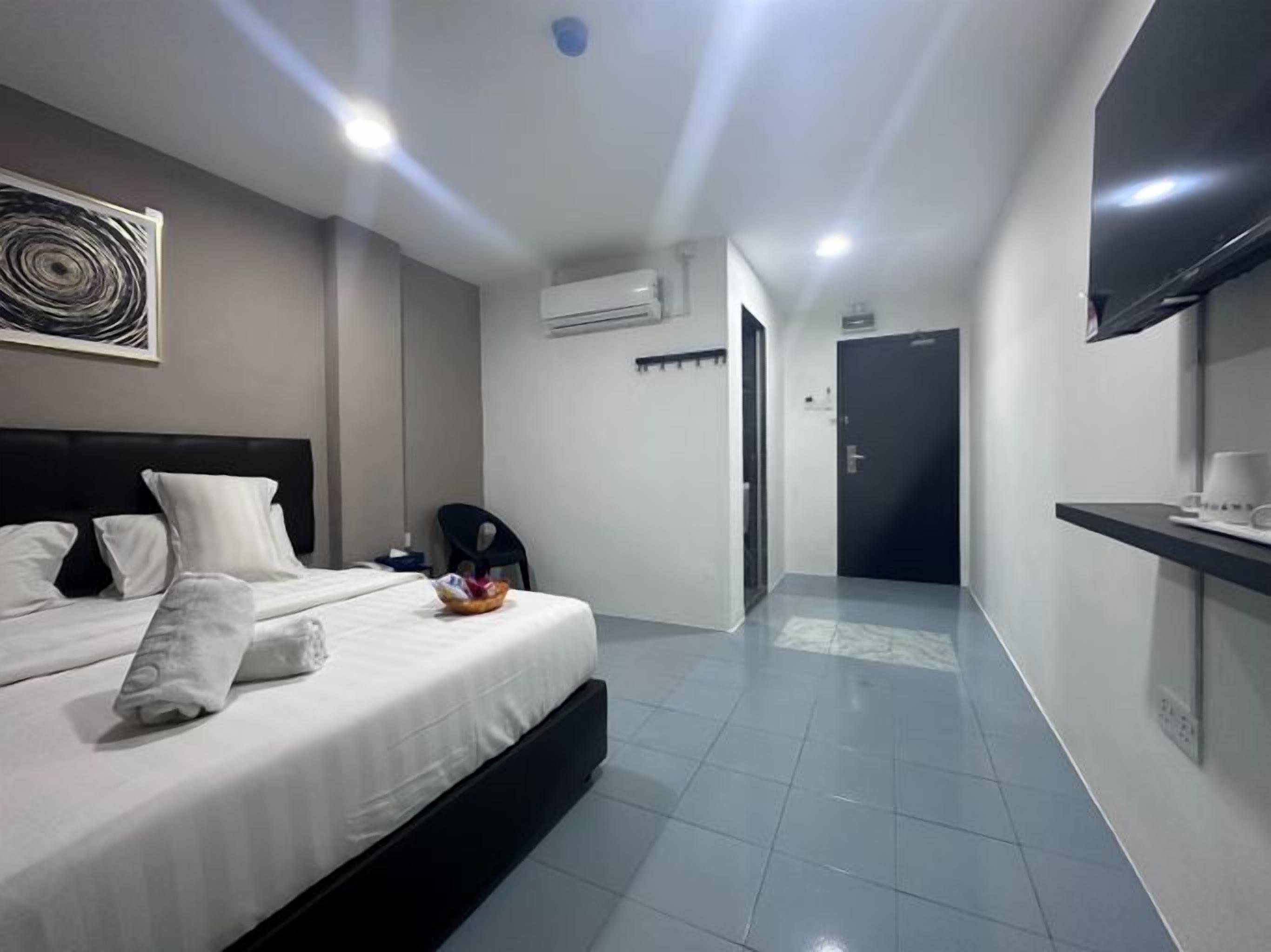 A hotel room with a bed, a flat-screen TV, a desk, and a chair.