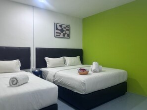 Une chambre d’hôtel avec deux lits, un mur d’accent de couleur verte et une œuvre d’art encadrée au-dessus des lits.