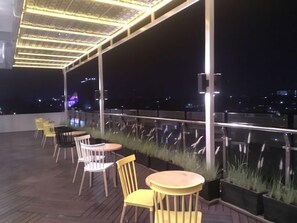 A rooftop terrace with outdoor seating and a view of the cityscape.