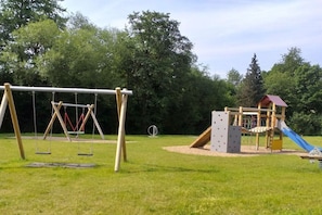 A playground with swings, a climbing structure, and a slide. - Holiday apartment with 2 bedrooms (Geiselwind)