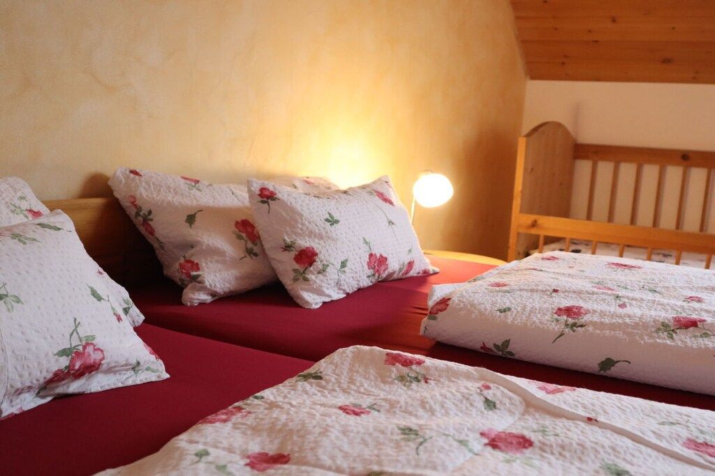 A bedroom with a wooden headboard, floral bedding, and a bedside lamp.