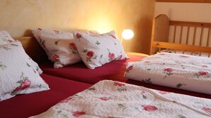 Un dormitorio con cabecera de madera, ropa de cama estampada con motivos florales y una lámpara de noche.