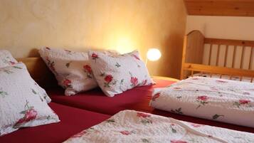 A bedroom with a wooden headboard, floral bedding, and a bedside lamp.