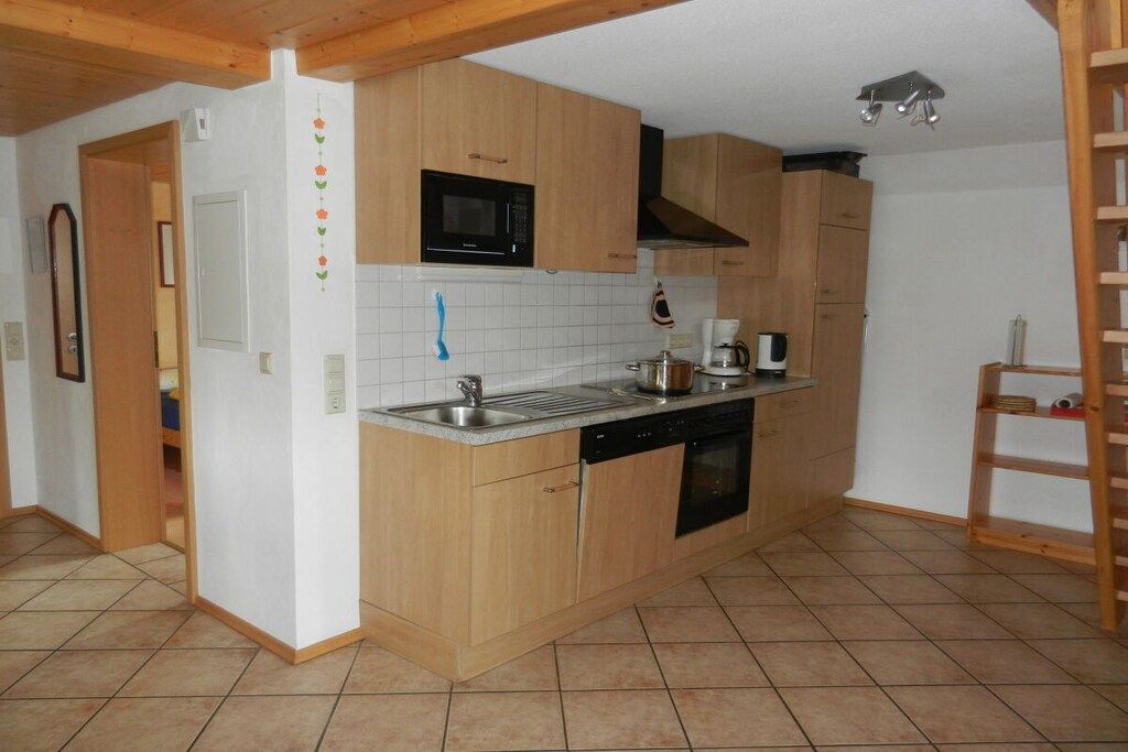 A compact kitchen with wooden cabinets, a microwave, a sink, and a dishwasher.