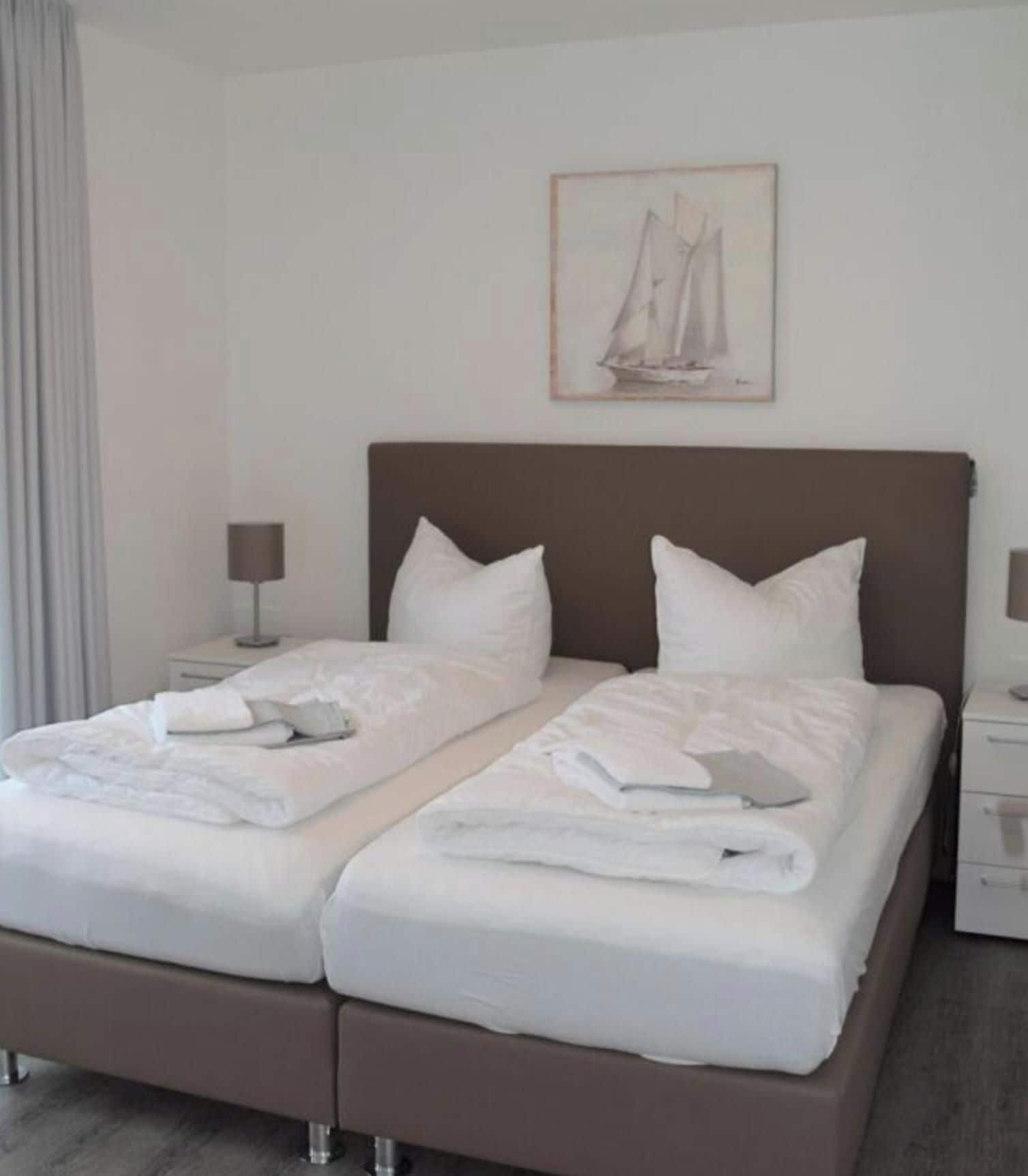 A double bed with white bedding, two bedside tables with lamps, and a framed picture on the wall.