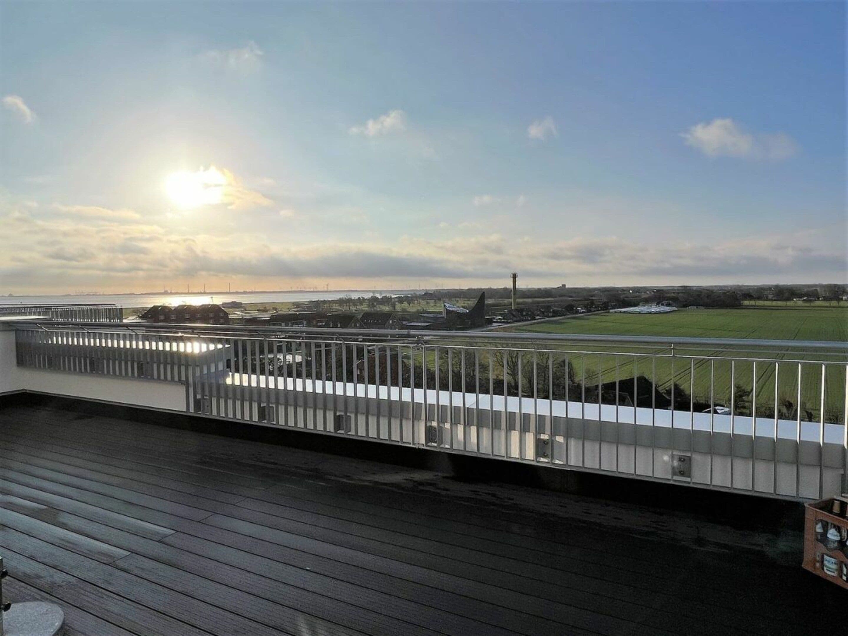 A view from a balcony overlooking a sports field with a clear sky and the sun setting or rising.