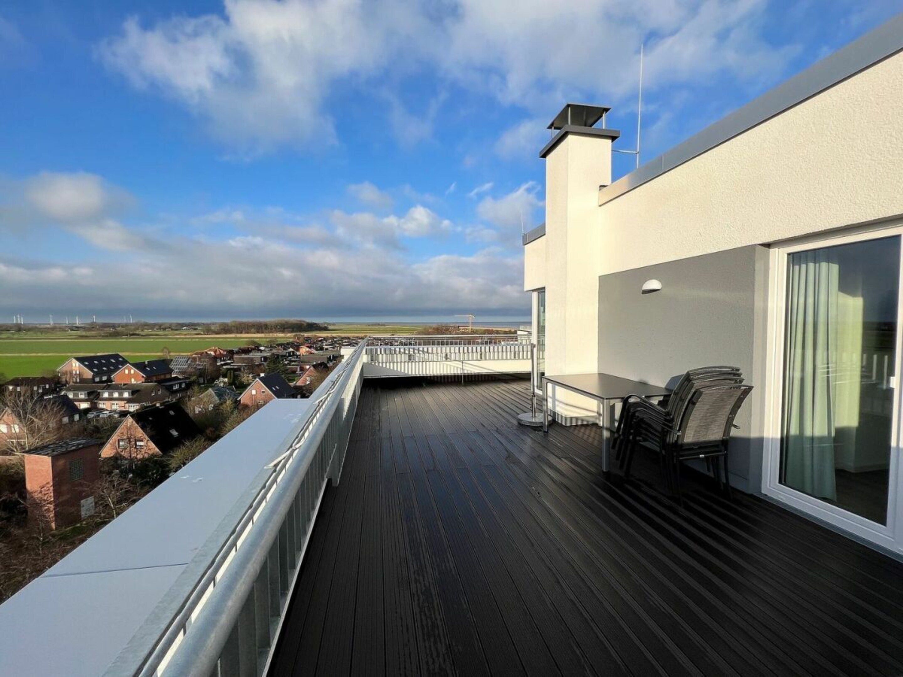 A balcony with a view of a residential area and a body of water.