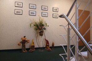 Eine Treppe mit Metallgeländern, eine Wand mit gerahmten Bildern und ein Blumentopf mit dekorativen Gartenzwergen.