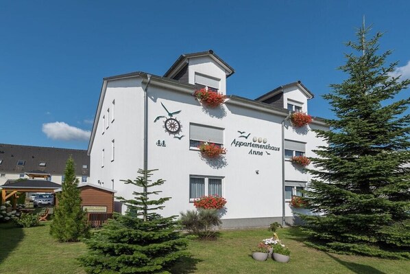 Un edificio bianco con la scritta 'Appartementhaus Anne' e una sveglia sulla facciata.
