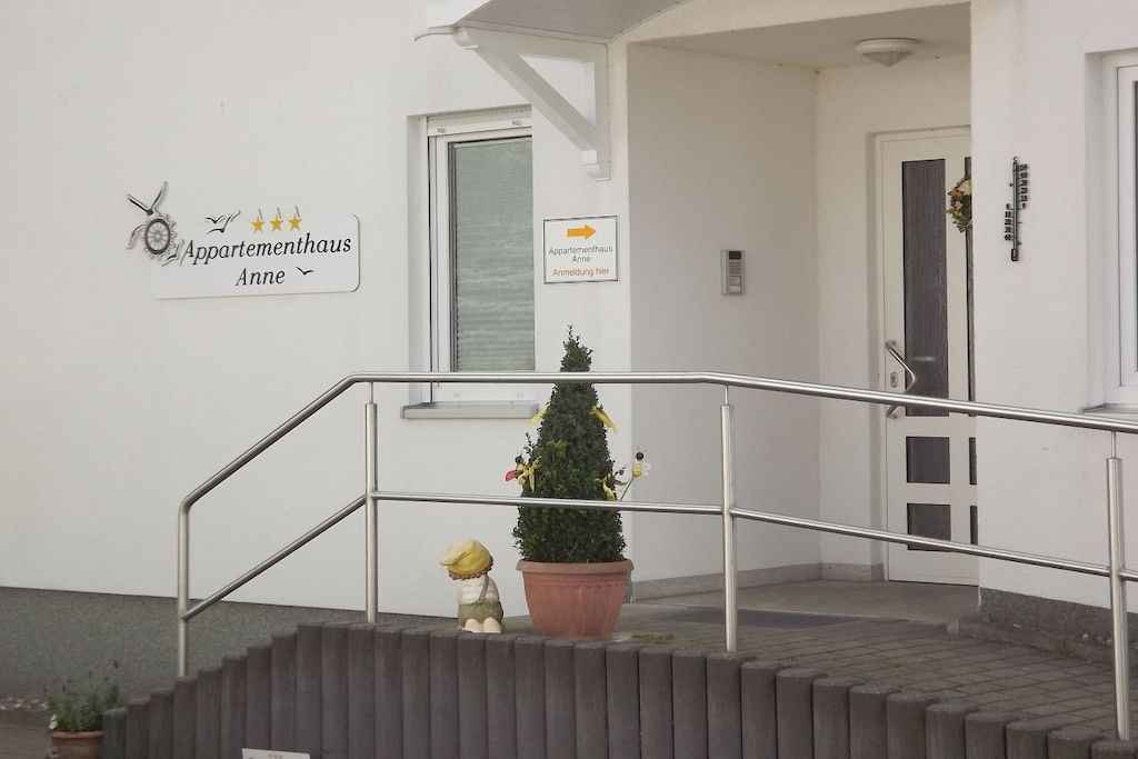 Une entrée d’immeuble avec un escalier, une petite plante en pot et une figurine décorative.