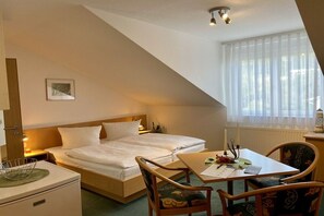 Ein Hotelzimmer mit Bett, Schreibtisch, Stuhl, Lampe und einem Fenster mit Vorhängen.