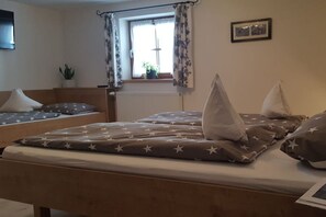 A bedroom with two beds, a window with curtains, a radiator, a plant, and a framed picture on the wall. - Holiday apartment with 2 bedrooms (Bad Hindelang)