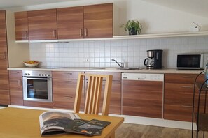 Eine moderne Küche mit Holzausstattung, einem Einbauofen, einer Kaffeemaschine und einem Geschirrspüler.