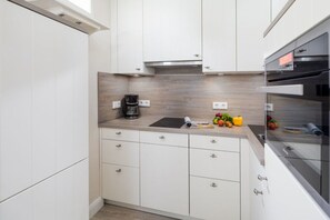 A modern kitchen with white cabinetry, a wooden countertop, and stainless steel appliances. - Kaiserhof 002 Reinke am Strand (Norderney)