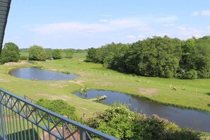 A view of a river with a bridge, surrounded by greenery and trees. - Holiday apartment in Süsel with swimming pool (Süsel)