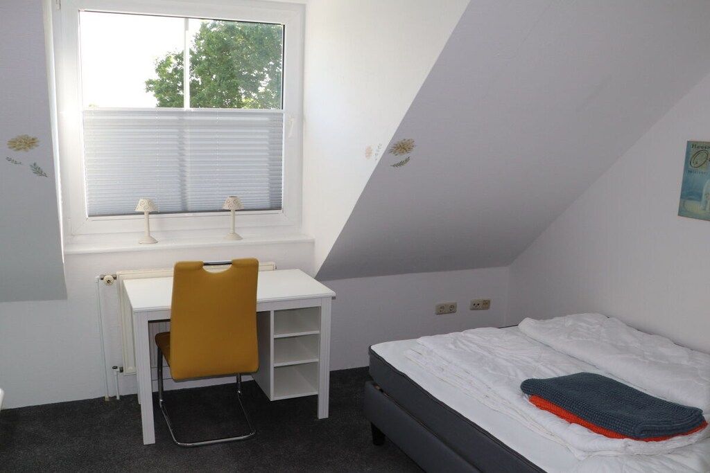 Une pièce comprenant un lit, un bureau avec une chaise, une fenêtre et un radiateur.