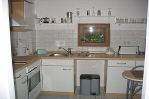 Une petite cuisine équipée d’une cuisinière, d’un évier et d’une poubelle.