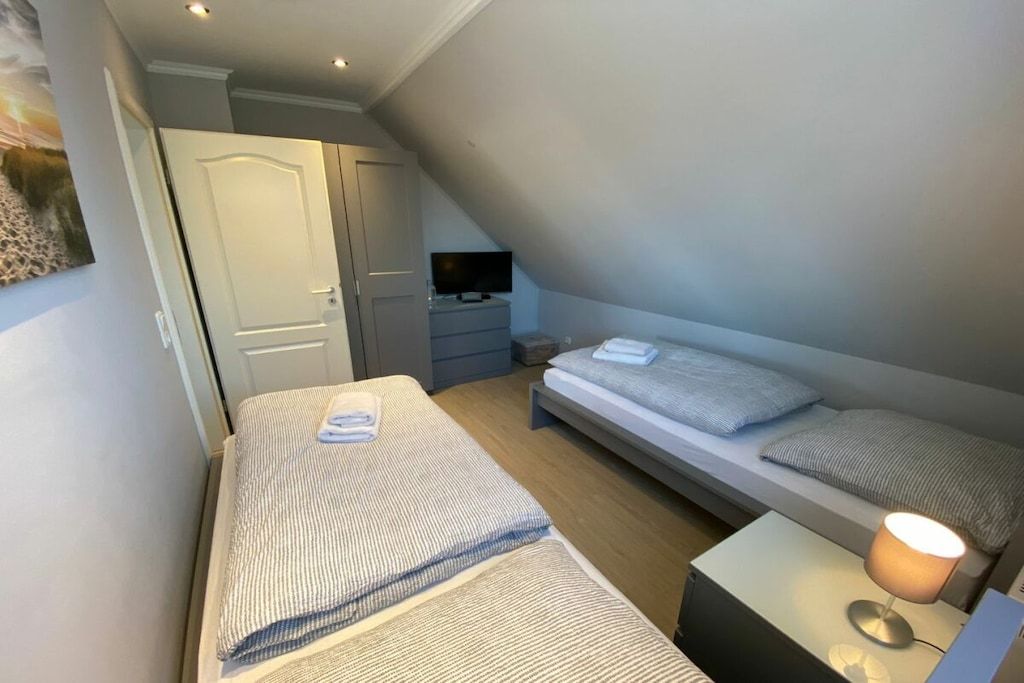 A bedroom with two beds, a TV, and a desk.