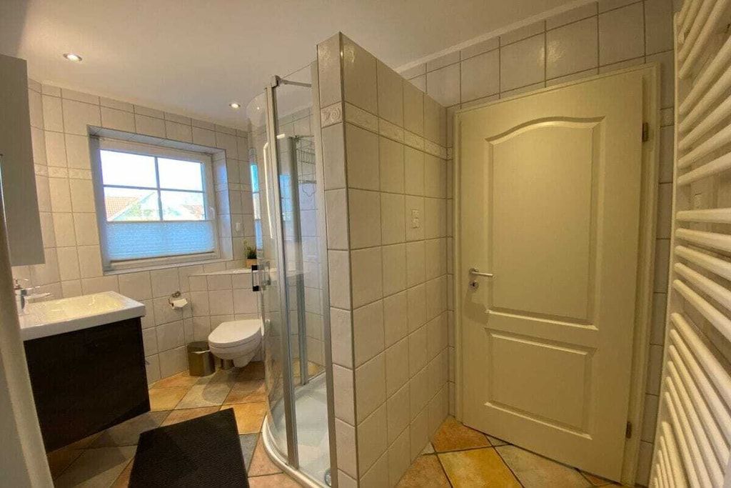 Ein Badezimmer mit Duschkabine aus Glas, Toilette und Waschbecken.