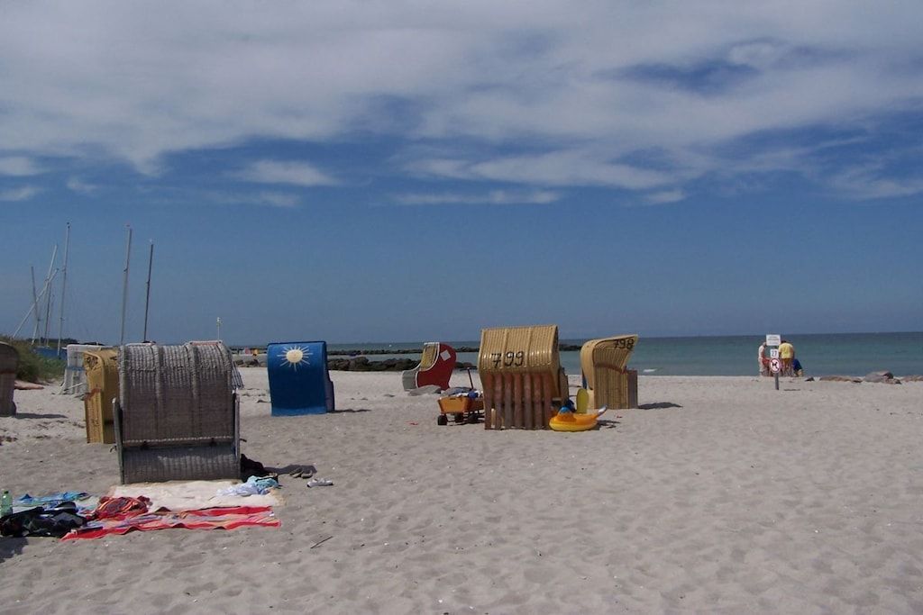 Een strand met ligbedden, een blauwe koelbox en een gele opblaasbare luchtbed.