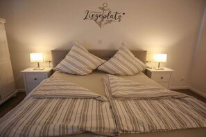 A bedroom with a bed, two bedside tables, and a wall-mounted sign. - Holiday apartment in Tetenbüll with sauna (Tetenbüll)