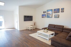 Ein Wohnzimmer mit einem braunen Sofa, einem weißen Couchtisch und einem flachbildfernseher an der Wand.