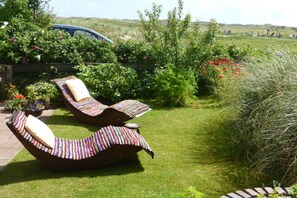 Ein Garten mit zwei Liegestühlen, einem Auto und verschiedenen Pflanzen.