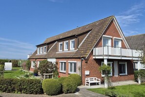 A two-story house with a sloped roof, a balcony, and a well-maintained garden. - Holiday apartment with 2 bedrooms (Fehmarn)