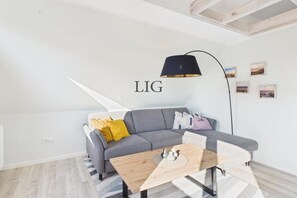 A modern living room with a grey sofa, a wooden coffee table, and a black floor lamp. - Holiday apartment Sanddorn (Langeoog)