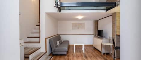 Un interior moderno con una escalera, un sofá, un televisor y un comedor.