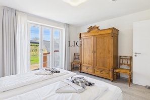 A hotel room with two beds, a wooden wardrobe, and a sliding glass door to the outside. - Holiday apartment Sandpiper (Langeoog)