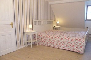 Une chambre à coucher avec un lit, une table de chevet, une lampe et une porte.