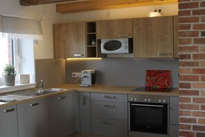 A kitchen with a microwave, oven, and coffee maker. - House Uhlenstraat - Apartment Käthe (Esgrus)