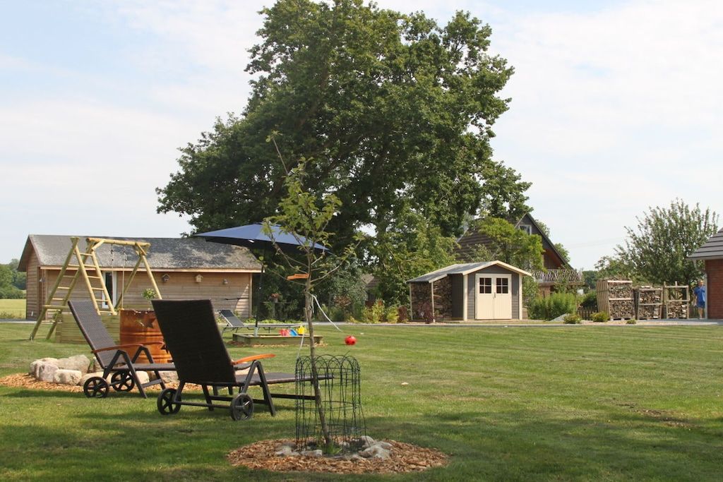Ein Garten mit Schaukel, kleiner Gartenhütte und Rasen.